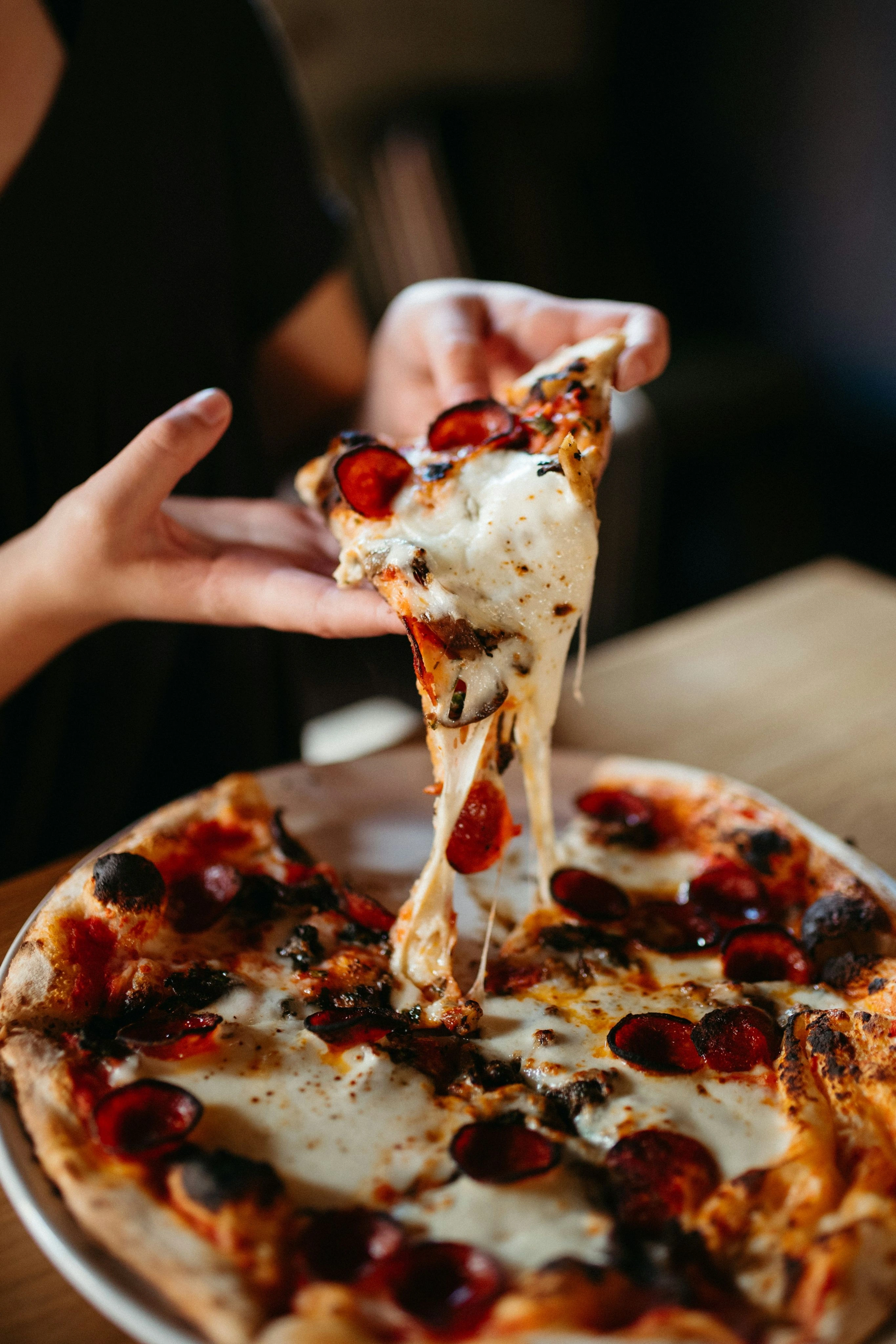 A slice lifted from a pizza with melted cheese